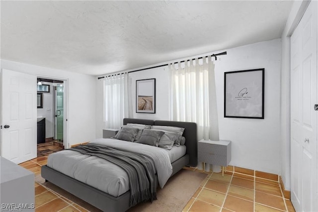 bedroom featuring connected bathroom and light tile patterned floors