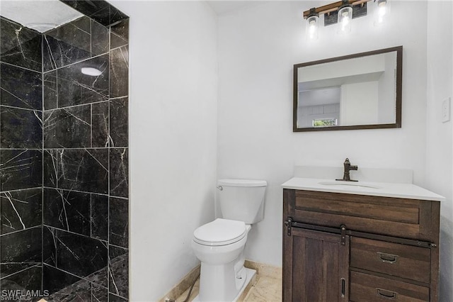 bathroom featuring tiled shower, vanity, and toilet