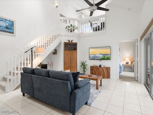 tiled living room with ceiling fan and a high ceiling