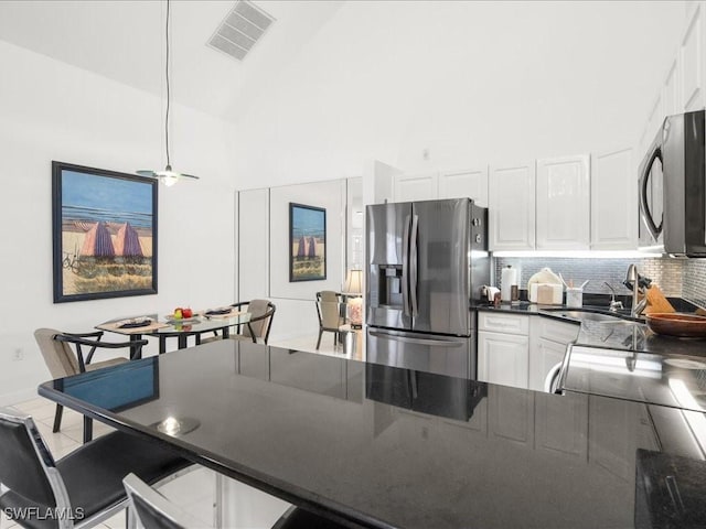 kitchen featuring decorative backsplash, sink, high vaulted ceiling, stainless steel fridge with ice dispenser, and white cabinetry