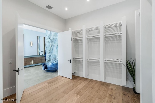 walk in closet with light hardwood / wood-style floors