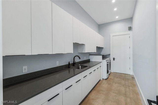 kitchen with independent washer and dryer, white cabinetry, and sink