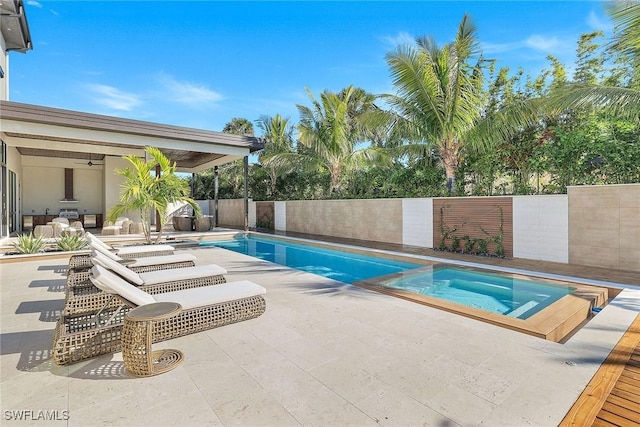 view of swimming pool with ceiling fan, a patio area, and an in ground hot tub