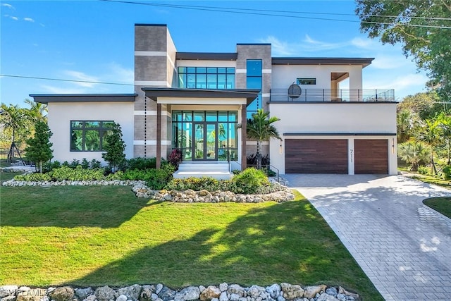 contemporary home featuring a garage, a balcony, a front yard, and french doors