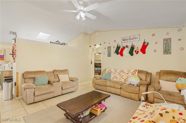 tiled living room with ceiling fan, high vaulted ceiling, and a skylight