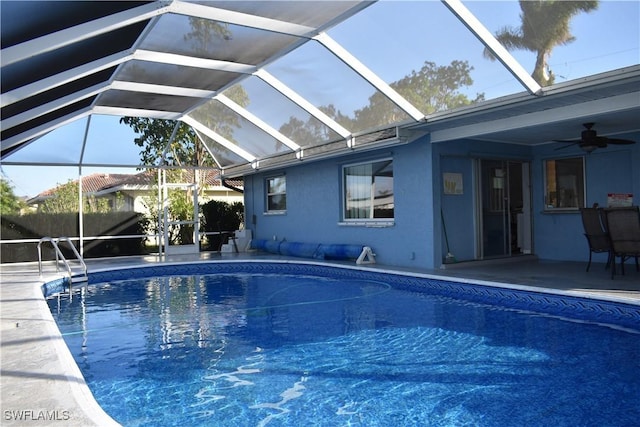 view of pool with a patio, glass enclosure, and ceiling fan