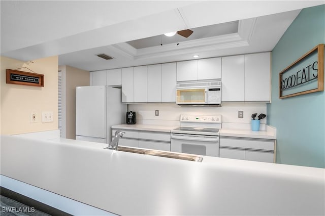 kitchen featuring white appliances, a raised ceiling, crown molding, sink, and white cabinetry