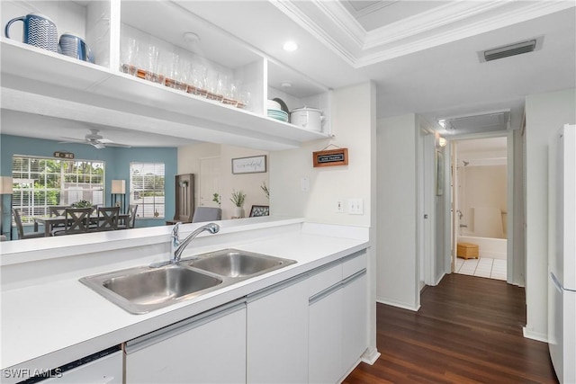 kitchen featuring dark hardwood / wood-style flooring, white dishwasher, crown molding, sink, and white cabinets