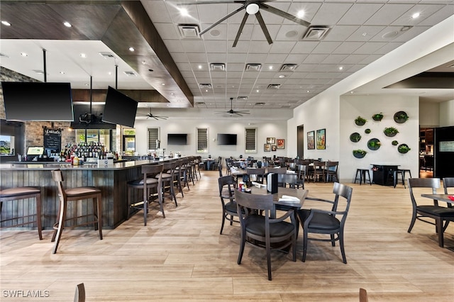 dining space featuring a drop ceiling, light hardwood / wood-style flooring, and ceiling fan