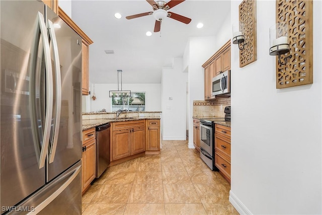 kitchen featuring decorative backsplash, appliances with stainless steel finishes, light stone counters, sink, and decorative light fixtures