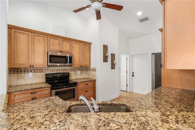 kitchen with high vaulted ceiling, sink, ceiling fan, appliances with stainless steel finishes, and stone countertops