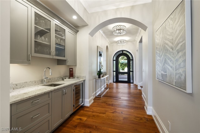 interior space featuring an inviting chandelier, sink, wine cooler, ornamental molding, and dark hardwood / wood-style flooring