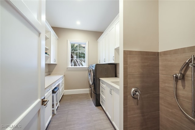 washroom featuring cabinets, washing machine and dryer, and light tile patterned flooring