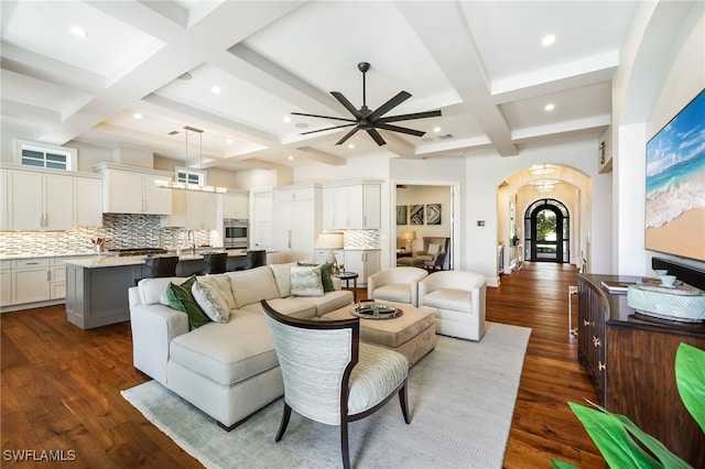 living room featuring beamed ceiling, dark hardwood / wood-style flooring, ceiling fan, and coffered ceiling