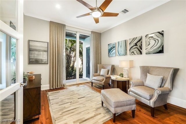 living area featuring a healthy amount of sunlight, ceiling fan, wood-type flooring, and ornamental molding