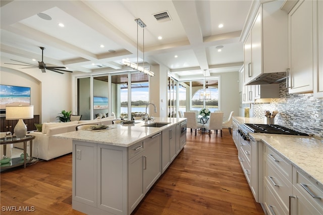 kitchen featuring light stone counters, a center island with sink, white cabinetry, and sink