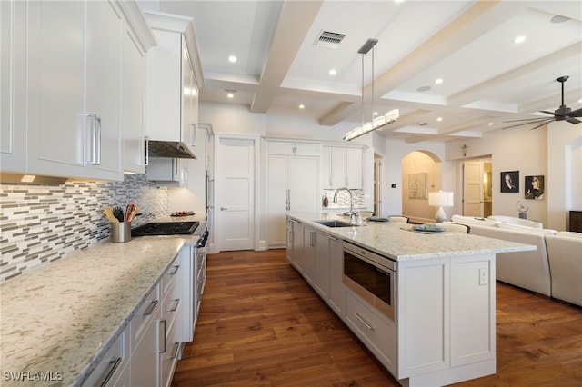 kitchen with beamed ceiling, white cabinets, and a kitchen island with sink