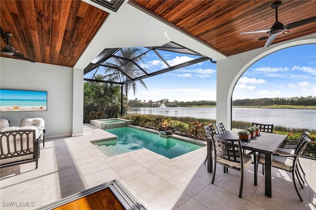 view of swimming pool with an in ground hot tub, ceiling fan, a water view, glass enclosure, and a patio