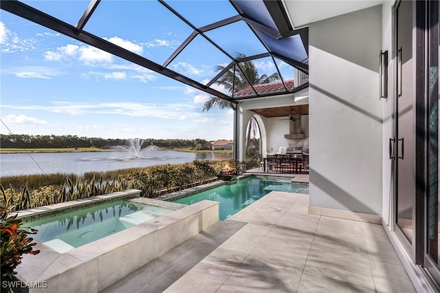 view of pool featuring glass enclosure, a water view, a patio, and an in ground hot tub