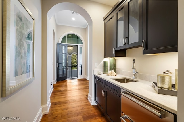 bar featuring hardwood / wood-style floors, light stone counters, sink, and stainless steel dishwasher