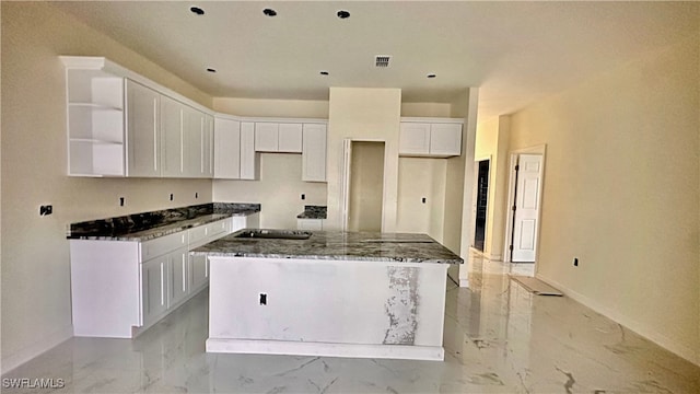 kitchen with dark stone countertops, white cabinetry, and a kitchen island