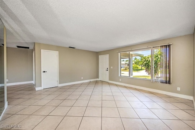 empty room with light tile patterned flooring and a textured ceiling