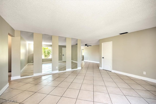 unfurnished room featuring ceiling fan, light tile patterned flooring, and a textured ceiling