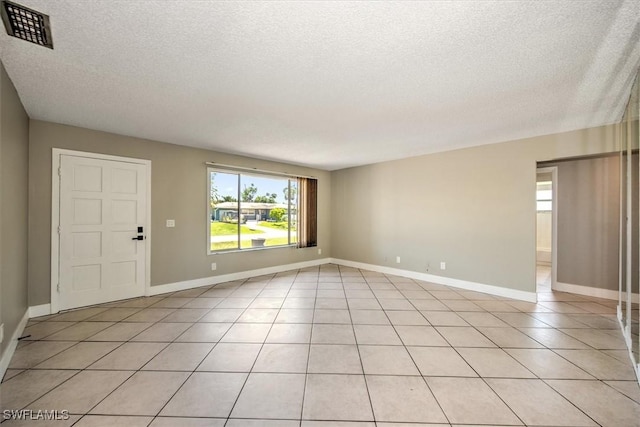 spare room featuring light tile patterned floors and a textured ceiling