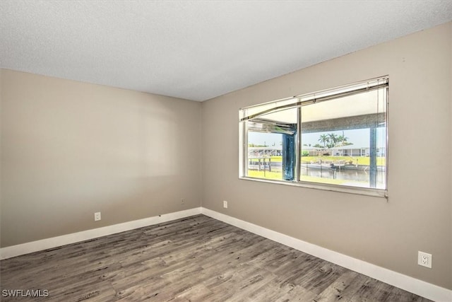 empty room featuring hardwood / wood-style floors, a textured ceiling, and a water view