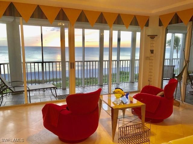 sunroom featuring a water view and a beach view