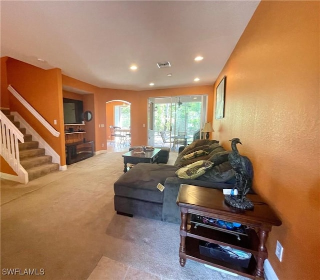 carpeted living room featuring stairway, visible vents, baseboards, recessed lighting, and arched walkways