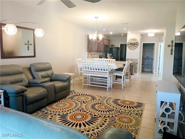 tiled living room with ceiling fan with notable chandelier