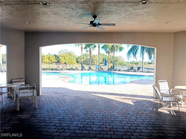 view of swimming pool featuring ceiling fan and a patio area