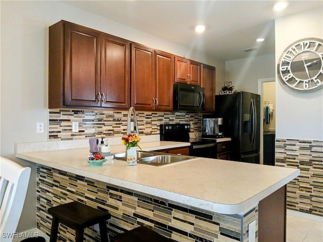 kitchen with black appliances, decorative backsplash, and kitchen peninsula