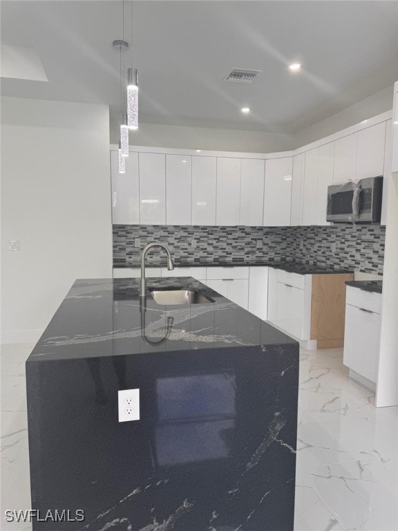 kitchen featuring white cabinetry, a center island with sink, and sink