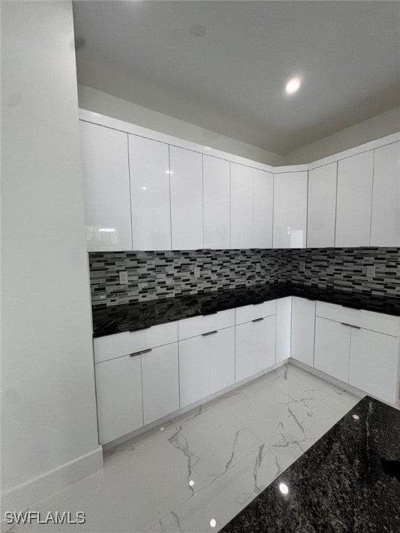 kitchen with white cabinets, backsplash, and dark stone countertops