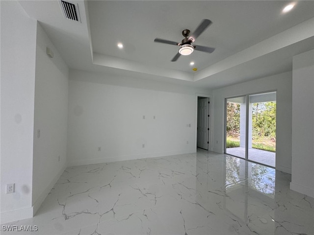 spare room featuring a tray ceiling and ceiling fan