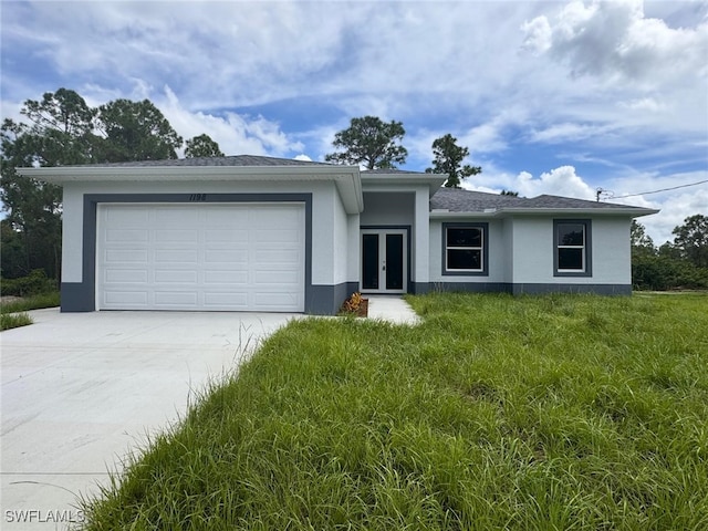 ranch-style home with a garage, a front yard, and french doors