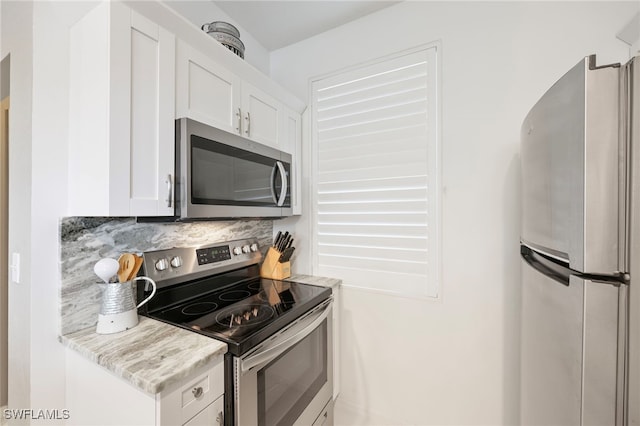 kitchen with light stone countertops, backsplash, stainless steel appliances, and white cabinetry