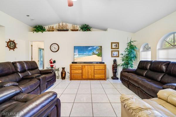 living room with ceiling fan, light tile patterned floors, and vaulted ceiling