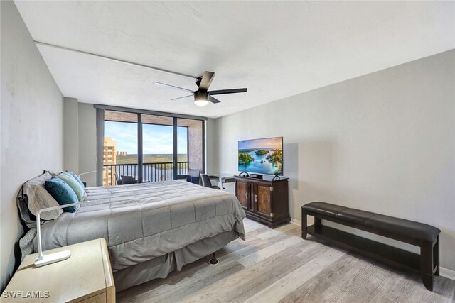 bedroom featuring access to exterior, light hardwood / wood-style floors, floor to ceiling windows, and ceiling fan