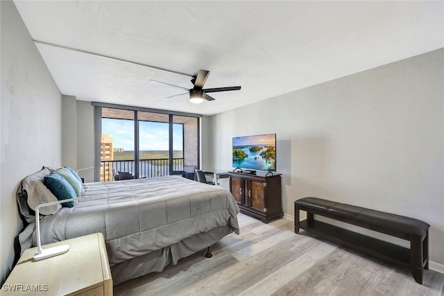 bedroom with ceiling fan, access to outside, light wood-type flooring, and a wall of windows