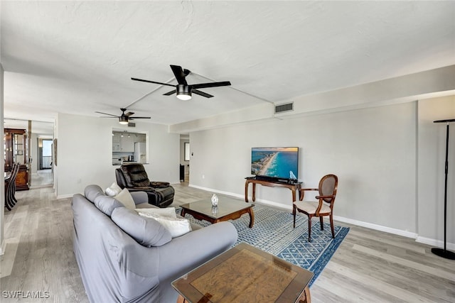 living room featuring ceiling fan, wood-type flooring, and a textured ceiling