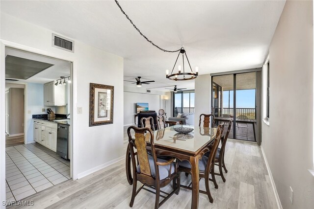 dining room with ceiling fan with notable chandelier, light hardwood / wood-style flooring, and expansive windows