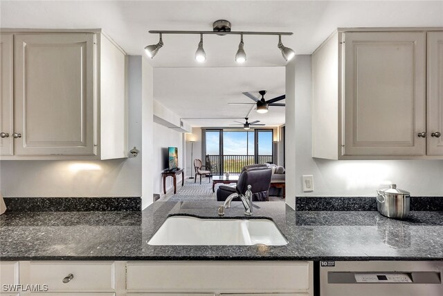 kitchen with dishwashing machine, dark stone countertops, sink, and decorative light fixtures