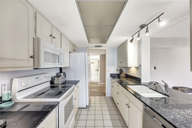 kitchen featuring sink, white appliances, light tile patterned floors, dark stone countertops, and white cabinets