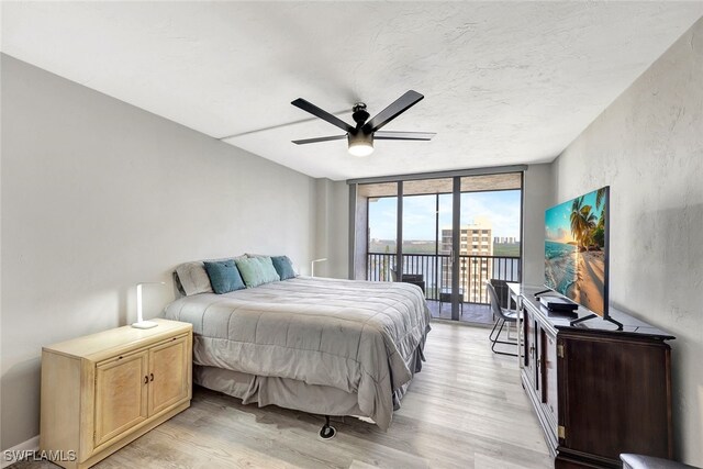 bedroom featuring a wall of windows, a textured ceiling, light wood-type flooring, ceiling fan, and access to exterior