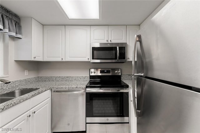 kitchen featuring light stone countertops, white cabinetry, appliances with stainless steel finishes, and sink