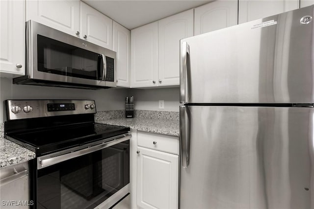 kitchen with appliances with stainless steel finishes, white cabinetry, and light stone counters