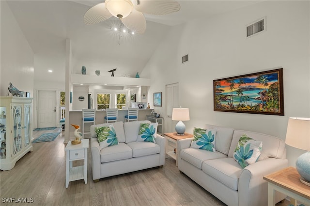 living room with ceiling fan, high vaulted ceiling, and light hardwood / wood-style flooring